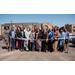  A big group of individuals smiling behind a ceremonial ribbon. 