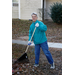 A woman in a teal jacket raking leaves. 