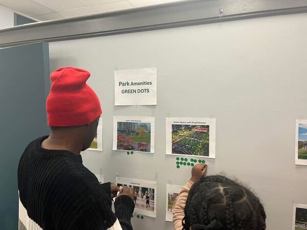 A man and child looking at a wall with printouts of Park Amenities, and putting green dots on it.
