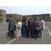  A group of individuals posing for a group photo in a parking lot. 
