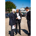  Three gentleman standing in a parking lot speaking. 